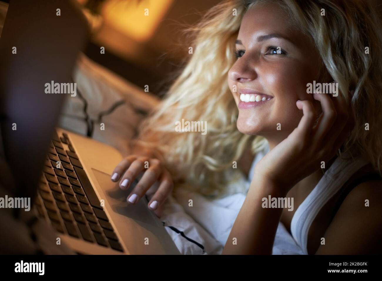 Socializzazione notturna online. Scatto di una giovane donna che usa il suo laptop sul suo letto di notte. Foto Stock