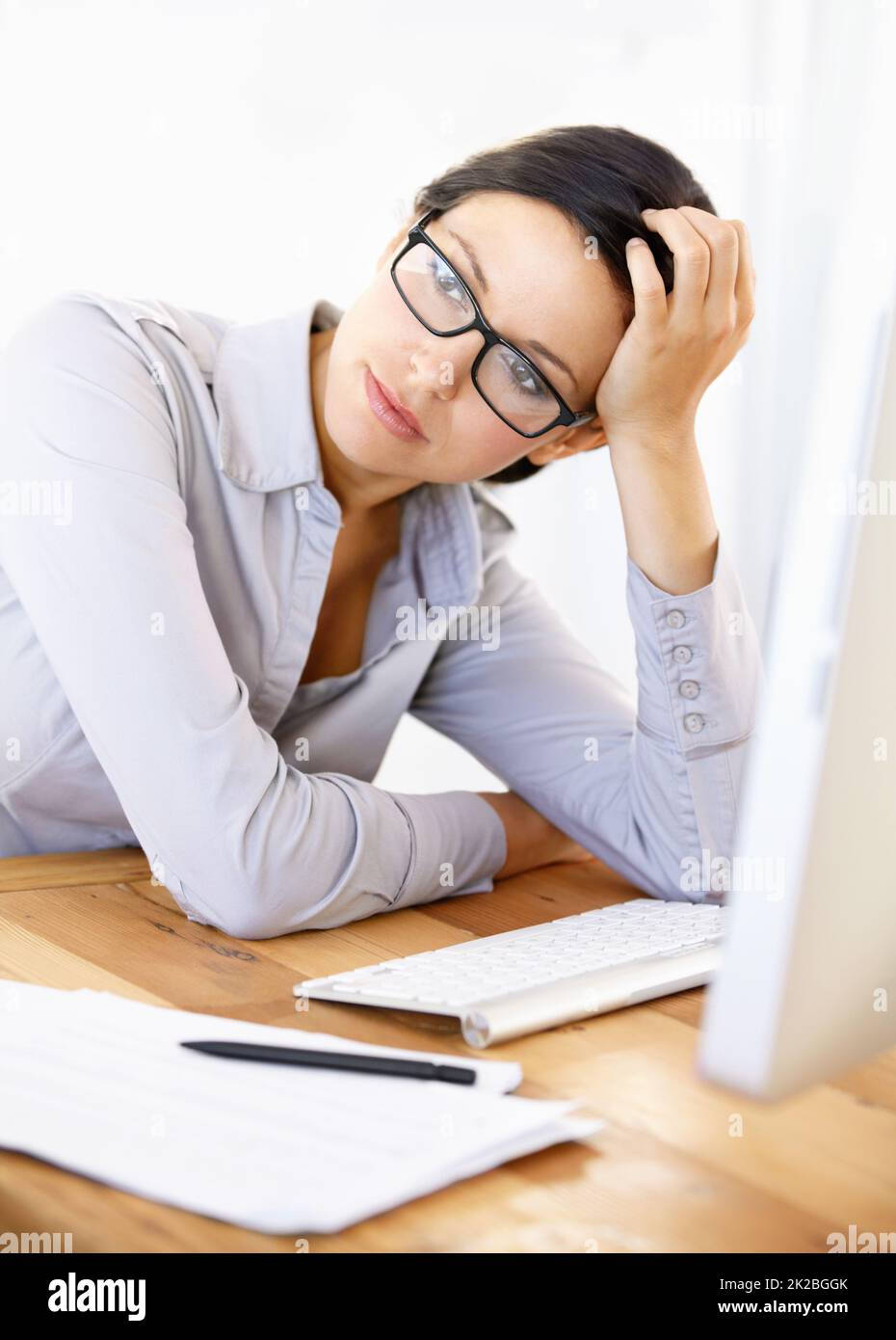 Annoiato della sua routine aziendale. Annoiato giovane donna d'affari seduta alla sua scrivania. Foto Stock