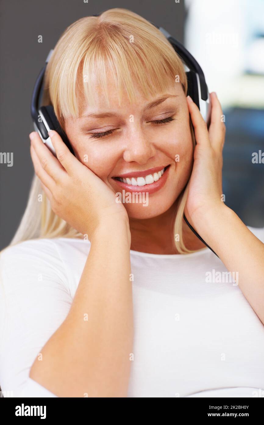 Donna con occhi chiusi ad ascoltare musica. Primo piano di una giovane donna rilassata che ascolta le cuffie. Foto Stock