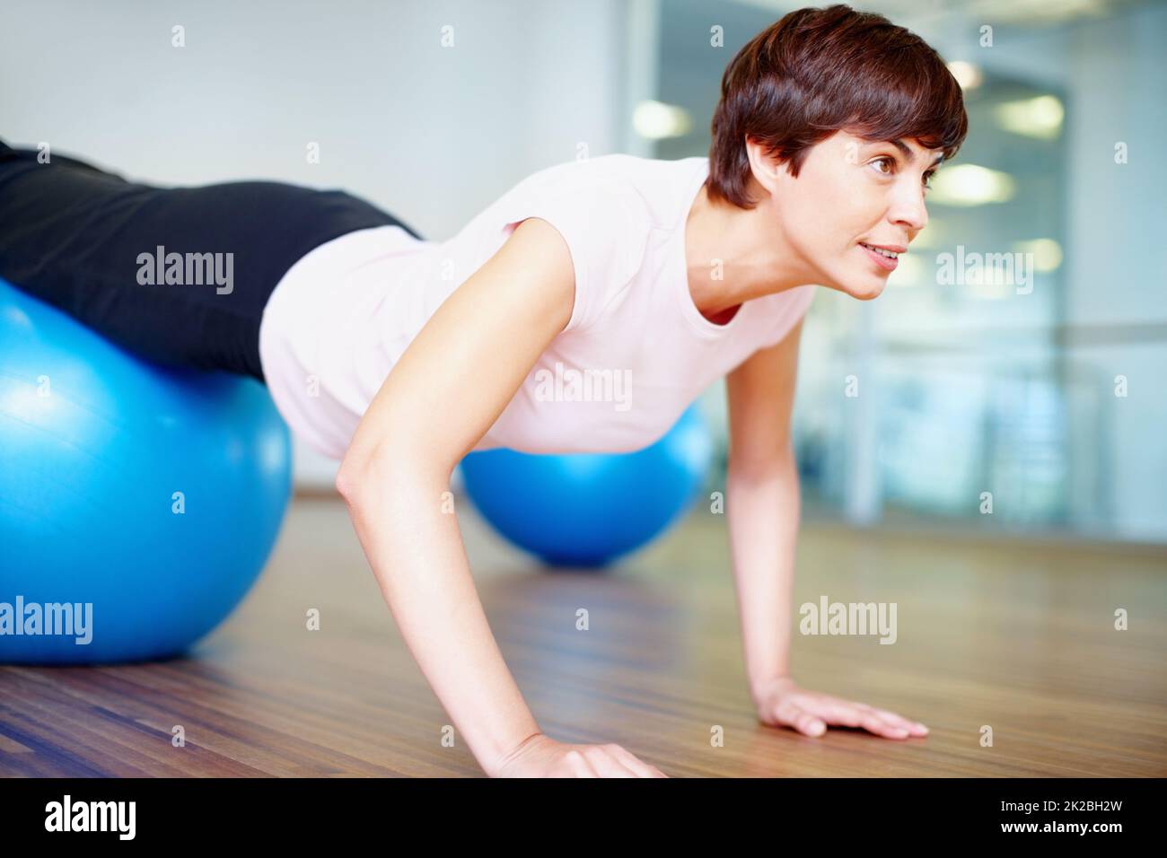 Spingere verso l'alto. Donna che fa push up utilizzando pilates palla durante una sessione di allenamento. Foto Stock