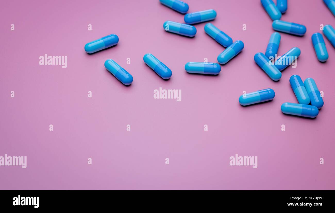 Vista dall'alto capsule pills su sfondo rosa. Farmaci da prescrizione. Capsule blu pillole. Industria farmaceutica. Medicamento e farmacologia. Sviluppo di farmaci e ricerca di nuovi farmaci. Capsule pills industria. Foto Stock