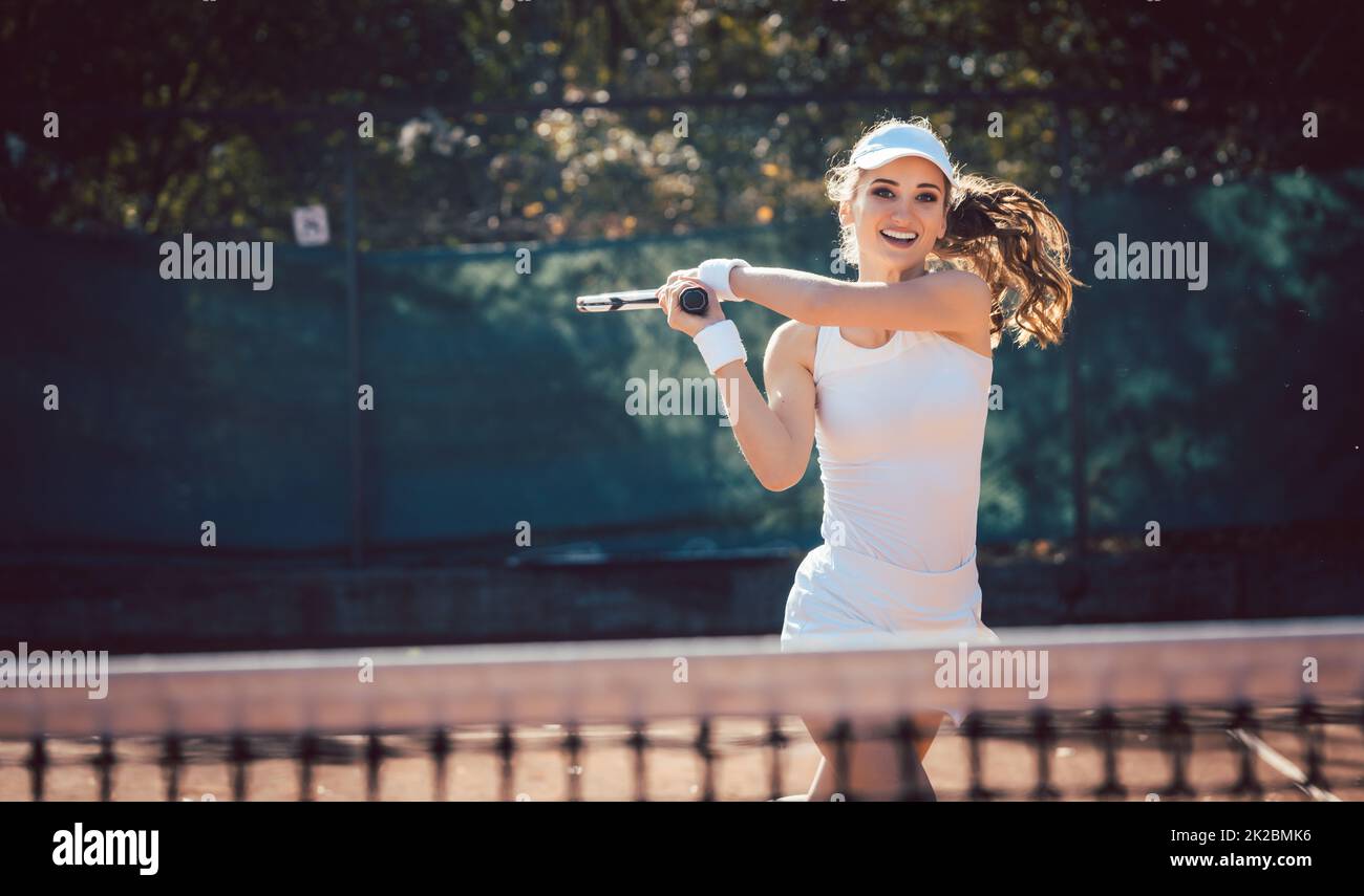Donna che gioca con forza a tennis in campo Foto Stock