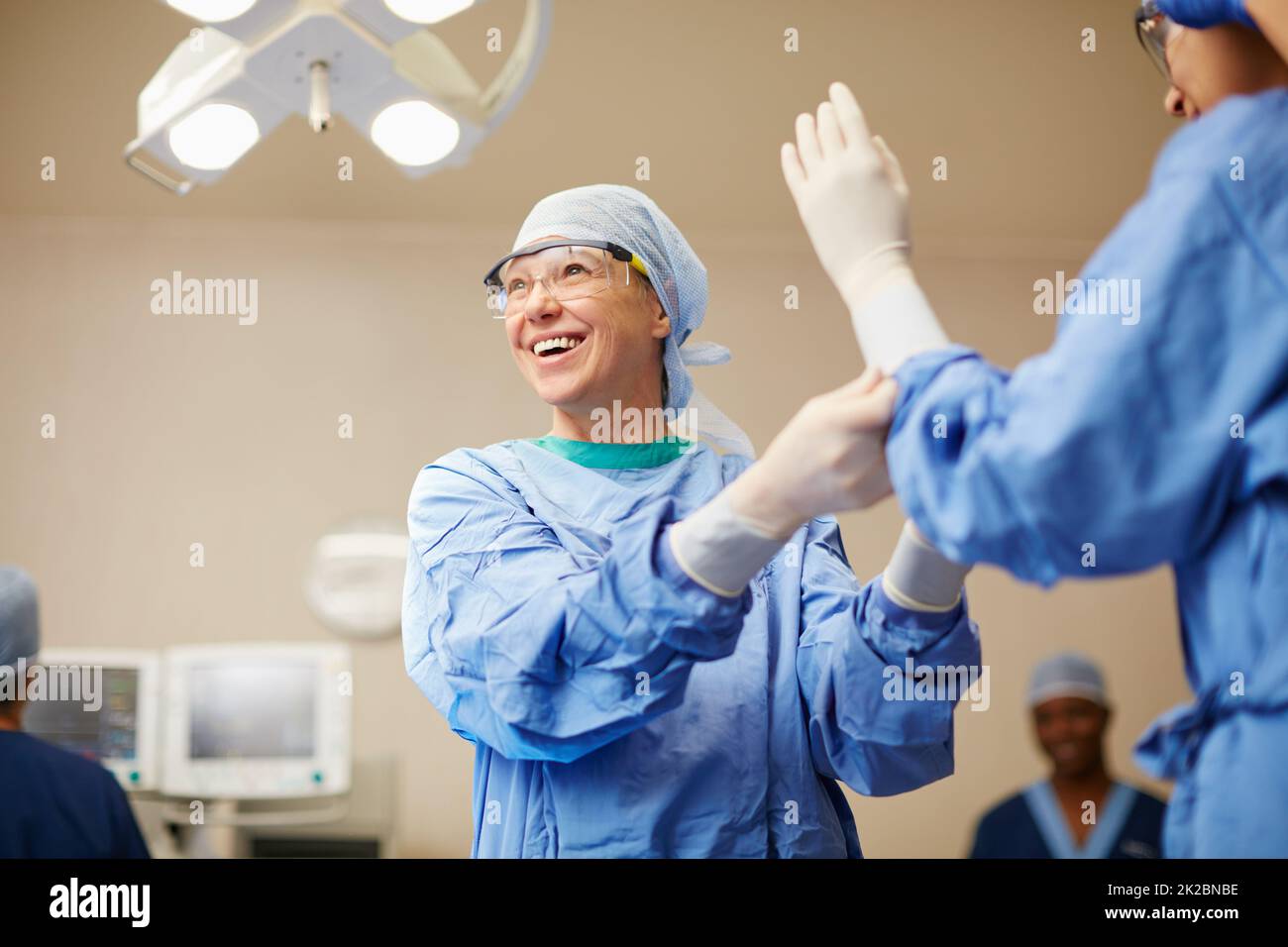 Proteggersi contro i germi. Shot di chirurghi che mettono su guanti chirurgici in preparazione per un intervento chirurgico. Foto Stock
