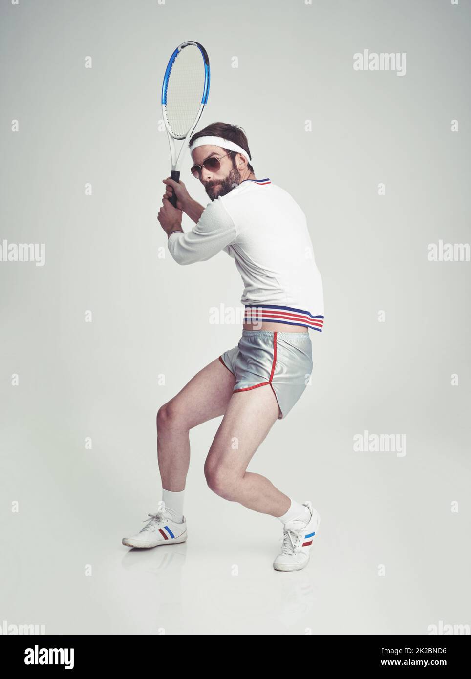 Fitness retrò. Un giovane uomo in studio che indossa l'attrezzatura da tennis. Foto Stock