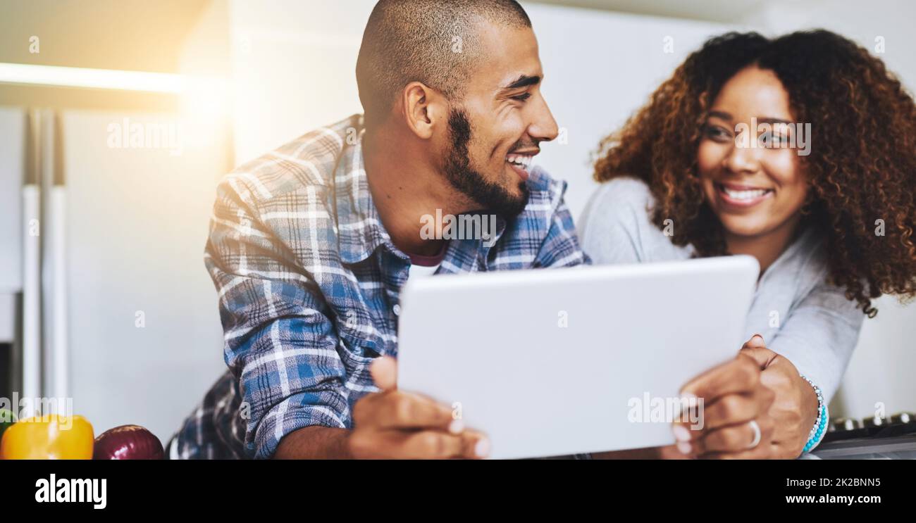 Stai pensando a cosa im pensare. Scatto di una giovane coppia usando un tablet insieme a casa. Foto Stock