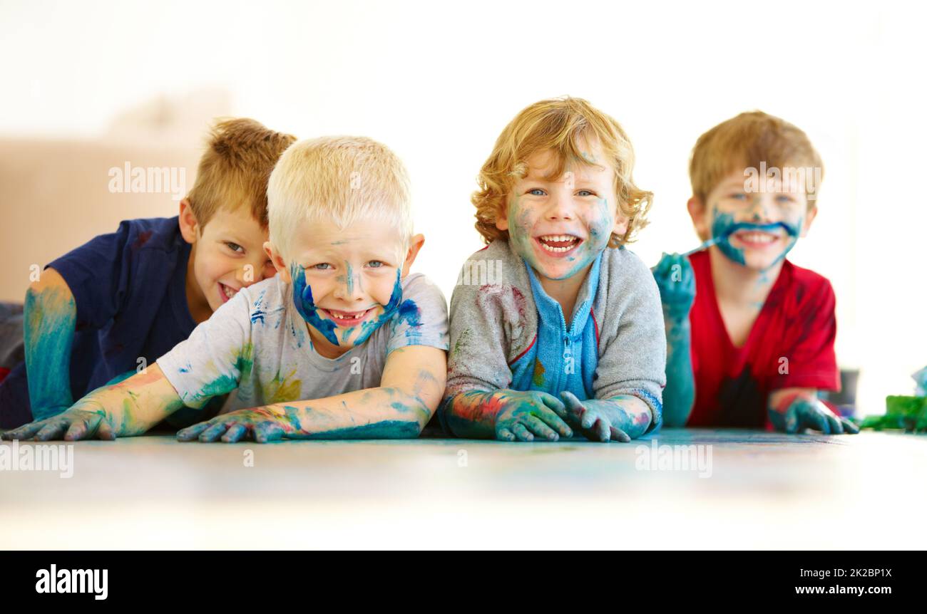 I bambini saranno bambini. Ritratto di quattro ragazzi carini ricoperti di vernice. Foto Stock