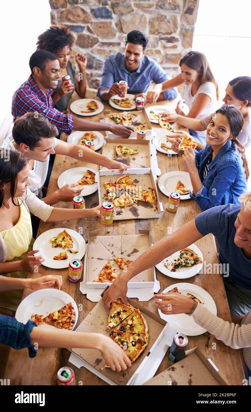 Riunirsi per la pizza. Un'immagine ritagliata di un gruppo di amici che si divertono con la pizza. Foto Stock