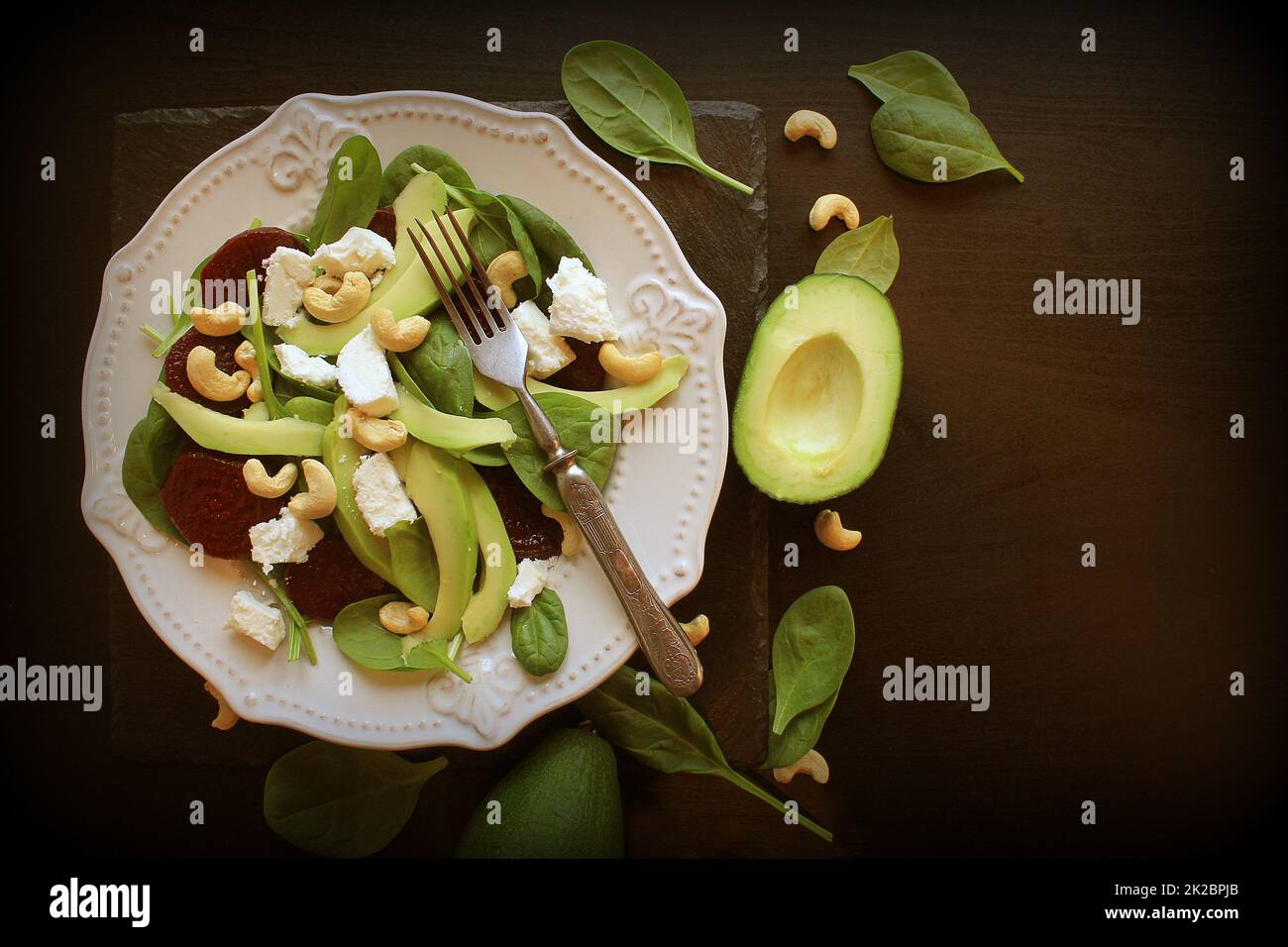 Sana Insalata di barbabietole con fresche dolci baby spinaci, dadi, il formaggio feta e avocado. Piastra con insalata scuro sul tavolo. Vista superiore Foto Stock