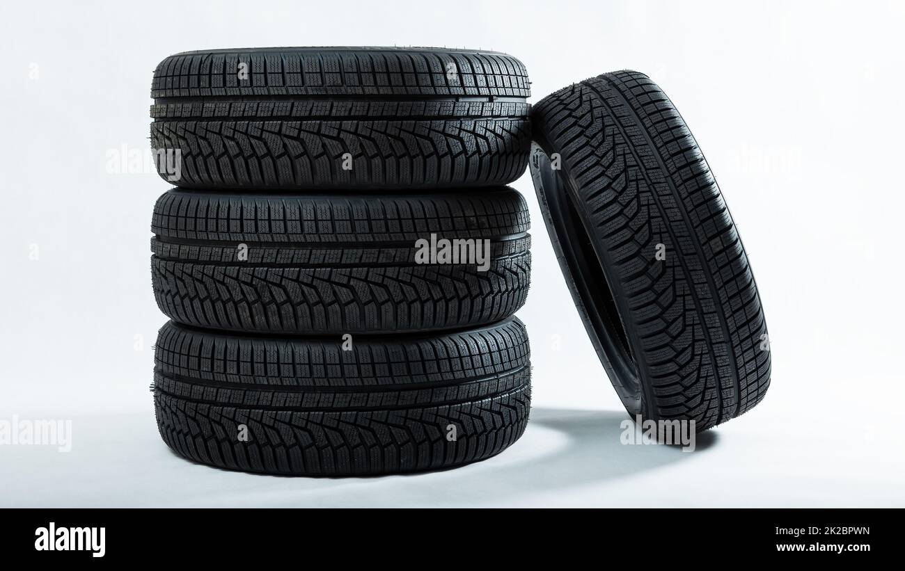 Pila di pneumatici con una ruota inclinata isolata su sfondo bianco Foto Stock