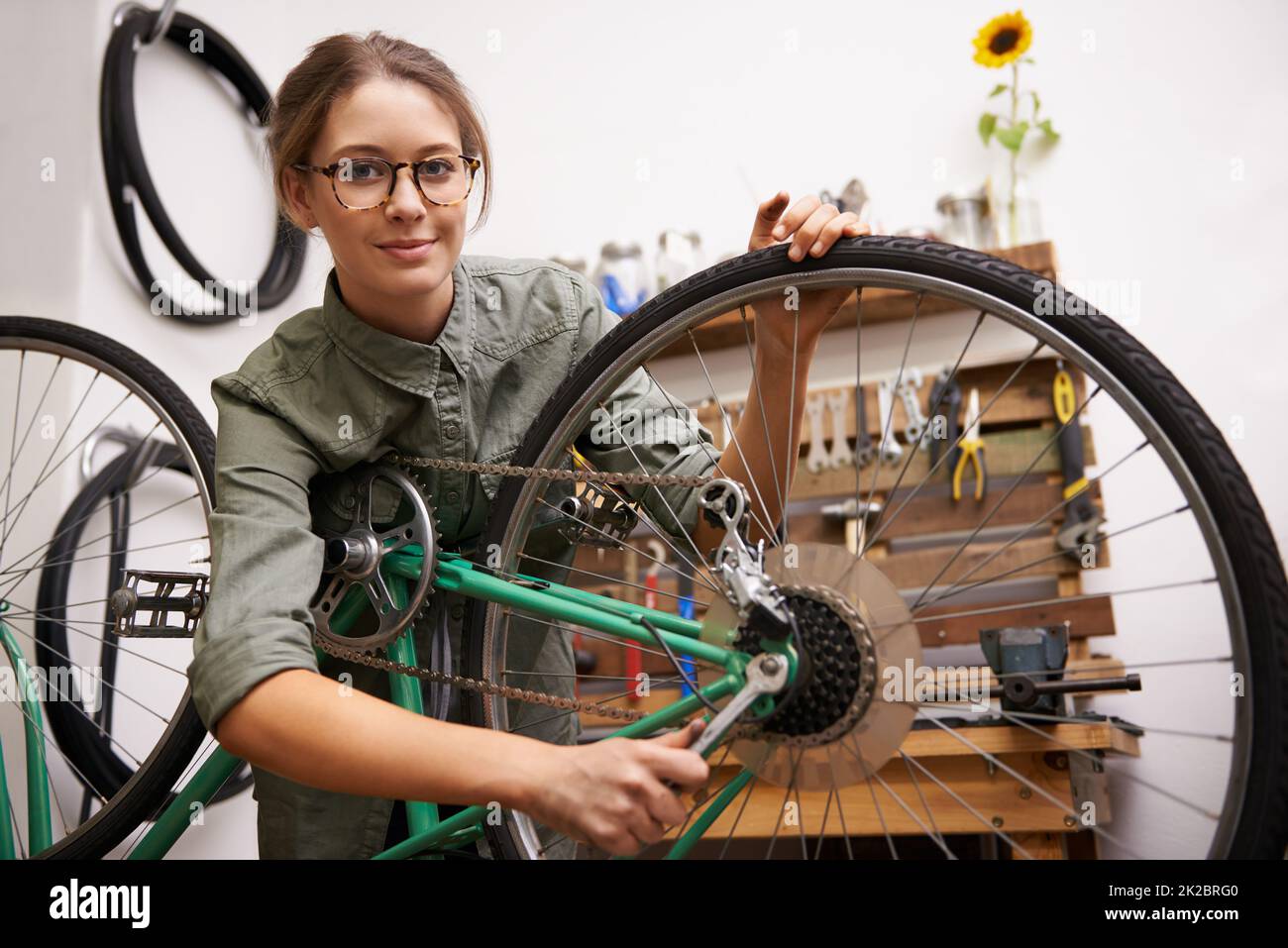 Le ragazze possono riparare le cose anche. Scatto di una giovane donna che guarda la macchina fotografica mentre fissa una bicicletta. Foto Stock