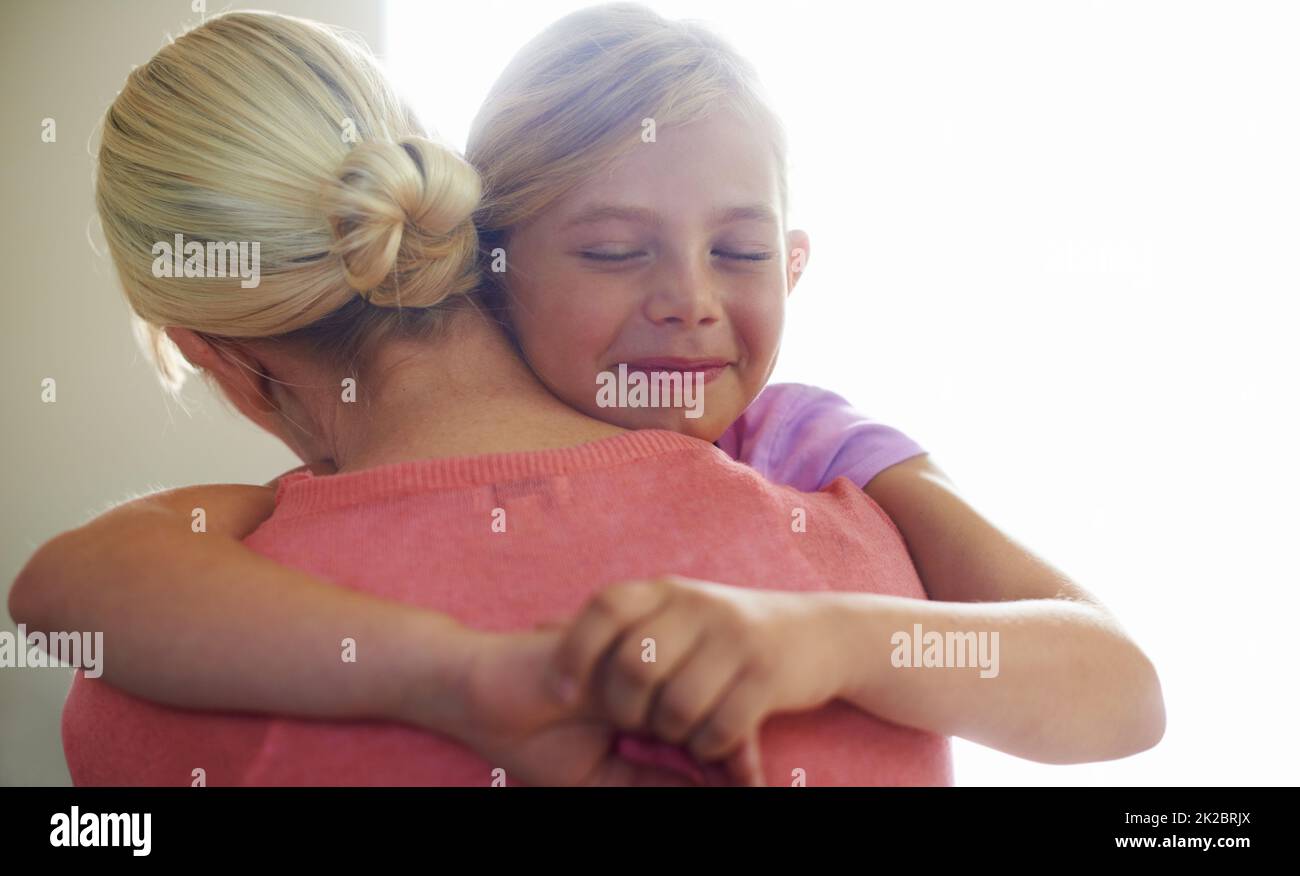 Ti amo tanto. Una ragazza piccola carina che abbraccia la mamma con un'espressione felice. Foto Stock