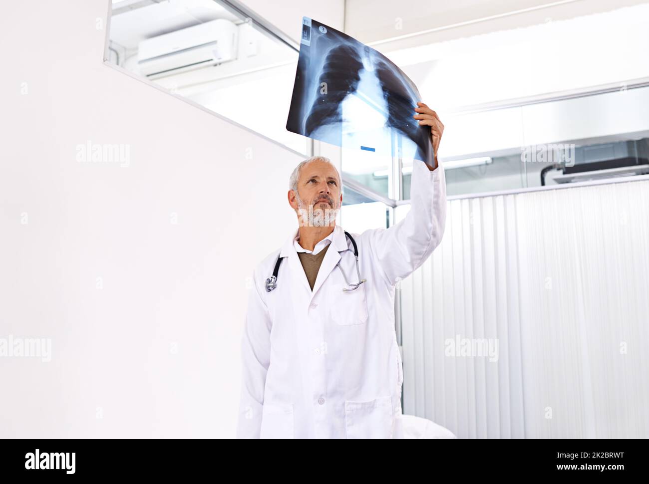 Scopri la tua gabbia a coste. Shot di un medico di sesso maschile maturo che esamina un'immagine radiografica in un ospedale. Foto Stock