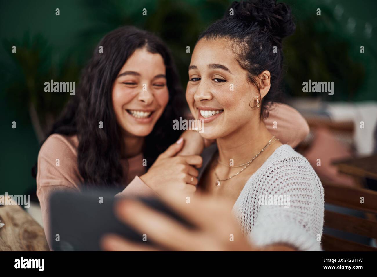 Le sorelle sono come gli amici tenuti per sempre nel cuore. Shot di giovani sorelle che prendono insieme i selfie in un caffè. Foto Stock