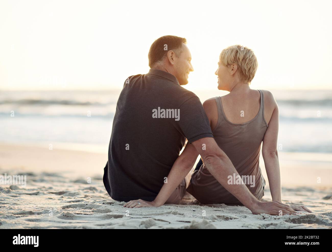 Guardando le maree rotolare con quello che amo. Una coppia amorevole seduta sulla spiaggia - vista posteriore. Foto Stock