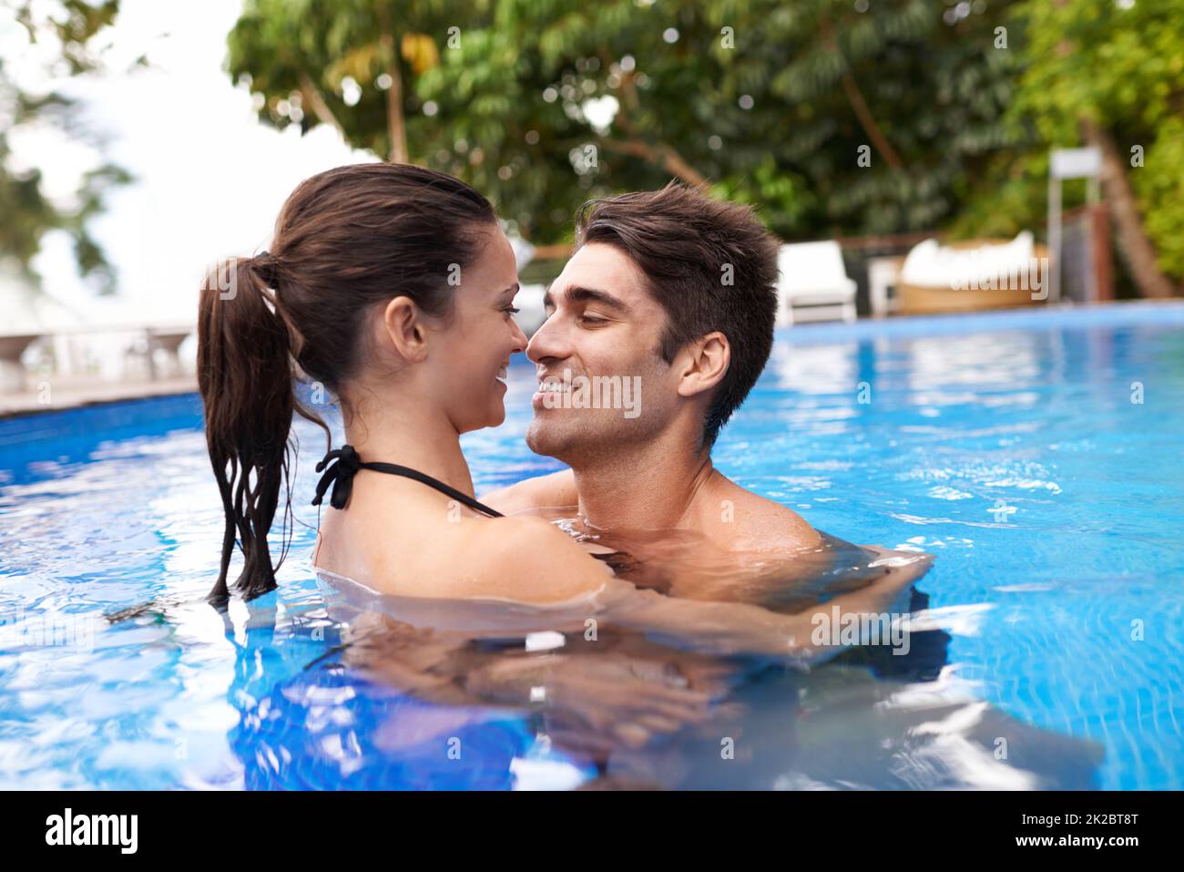 Riscaldamento in piscina. Scatto di una coppia giovane attraente che ottiene vicino in una piscina. Foto Stock