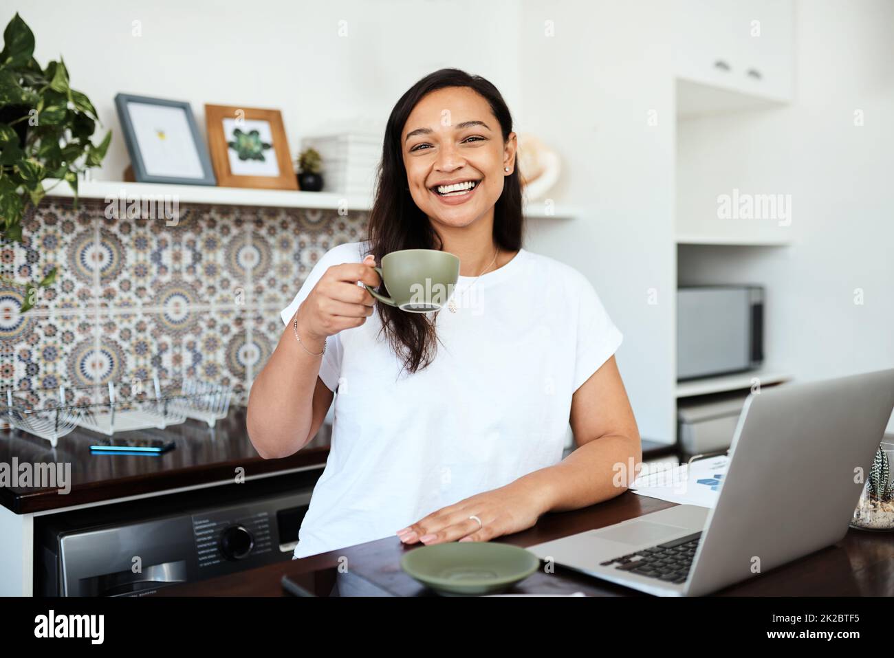 Non riesco ad iniziare senza caffè. Ritratto di una giovane donna che beve caffè mentre lavora su un notebook a casa. Foto Stock