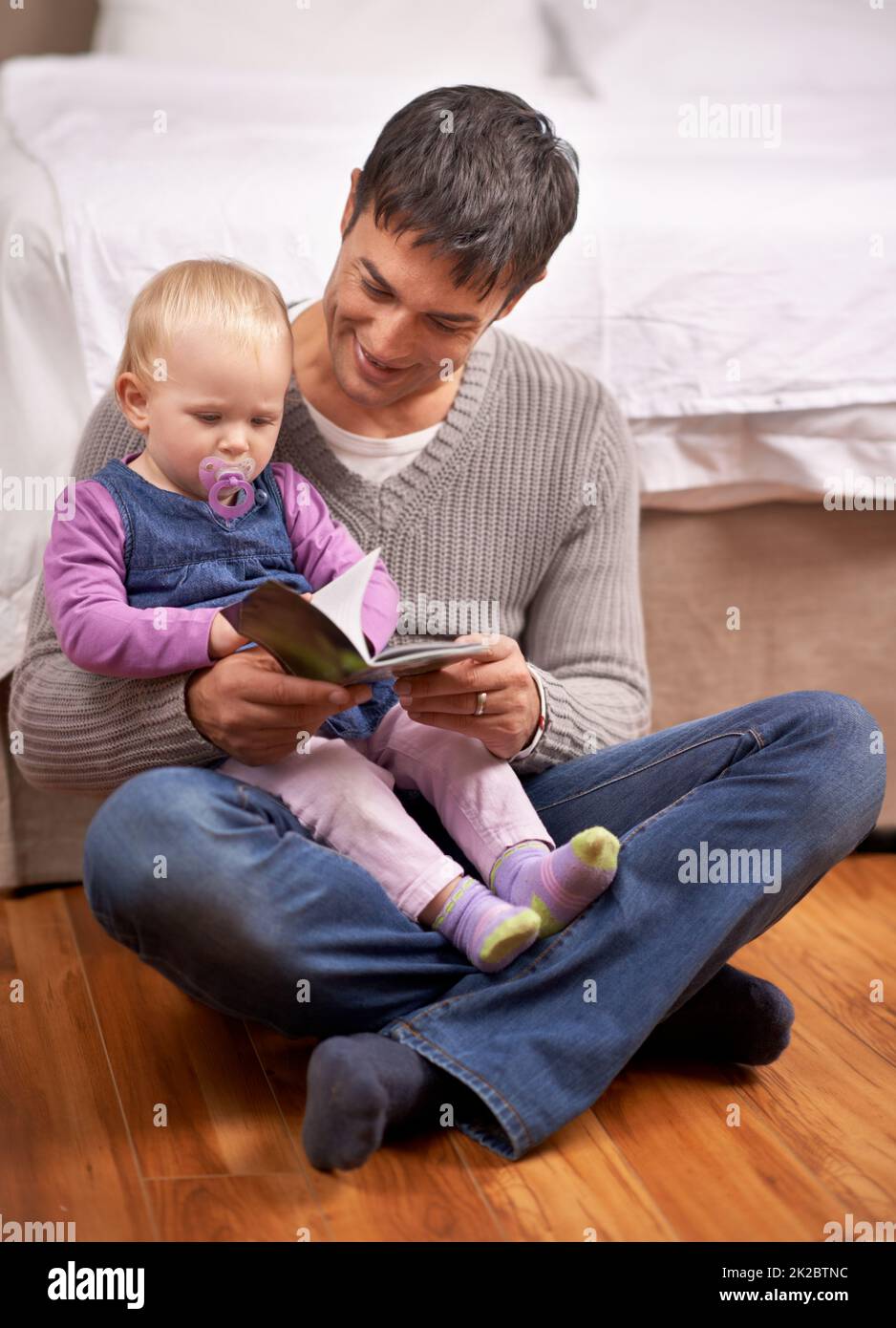 HES leggere il suo libro preferito. Un giovane padre che legge la sua bambina un libro di storia. Foto Stock