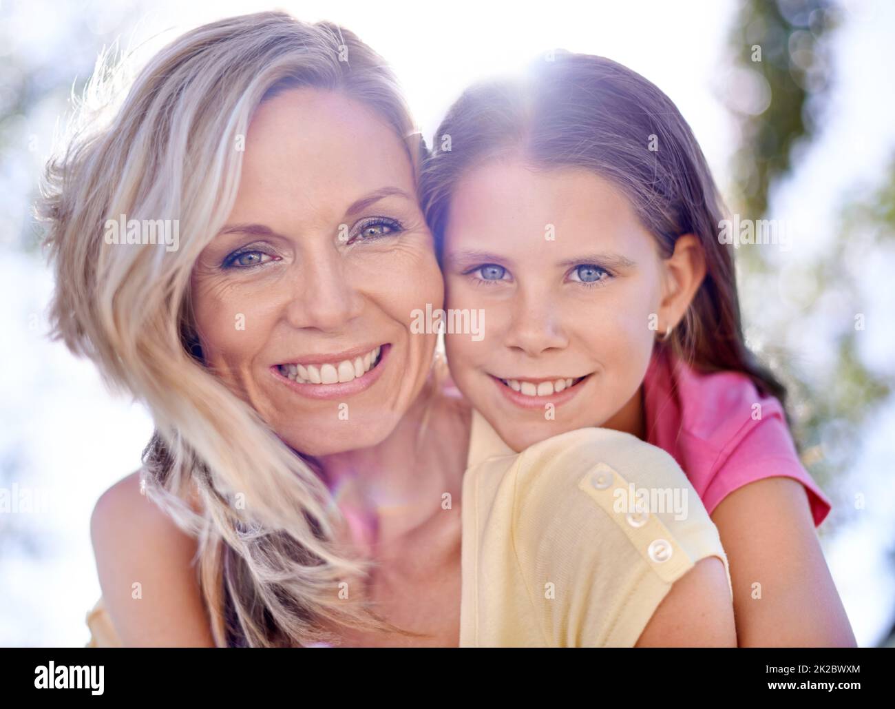 Condividere sorrisi corrispondenti. Una madre sorridente con la figlia sulla schiena mentre si trova all'aperto. Foto Stock