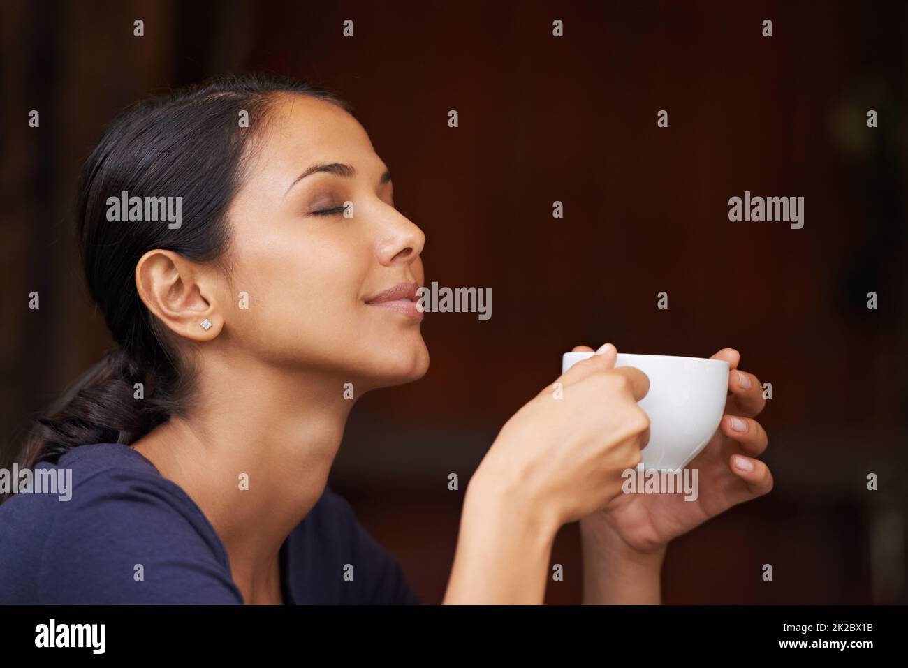 Il delizioso aroma di caffè appena macinato. Una giovane donna che beve una tazza di caffè all'aperto. Foto Stock