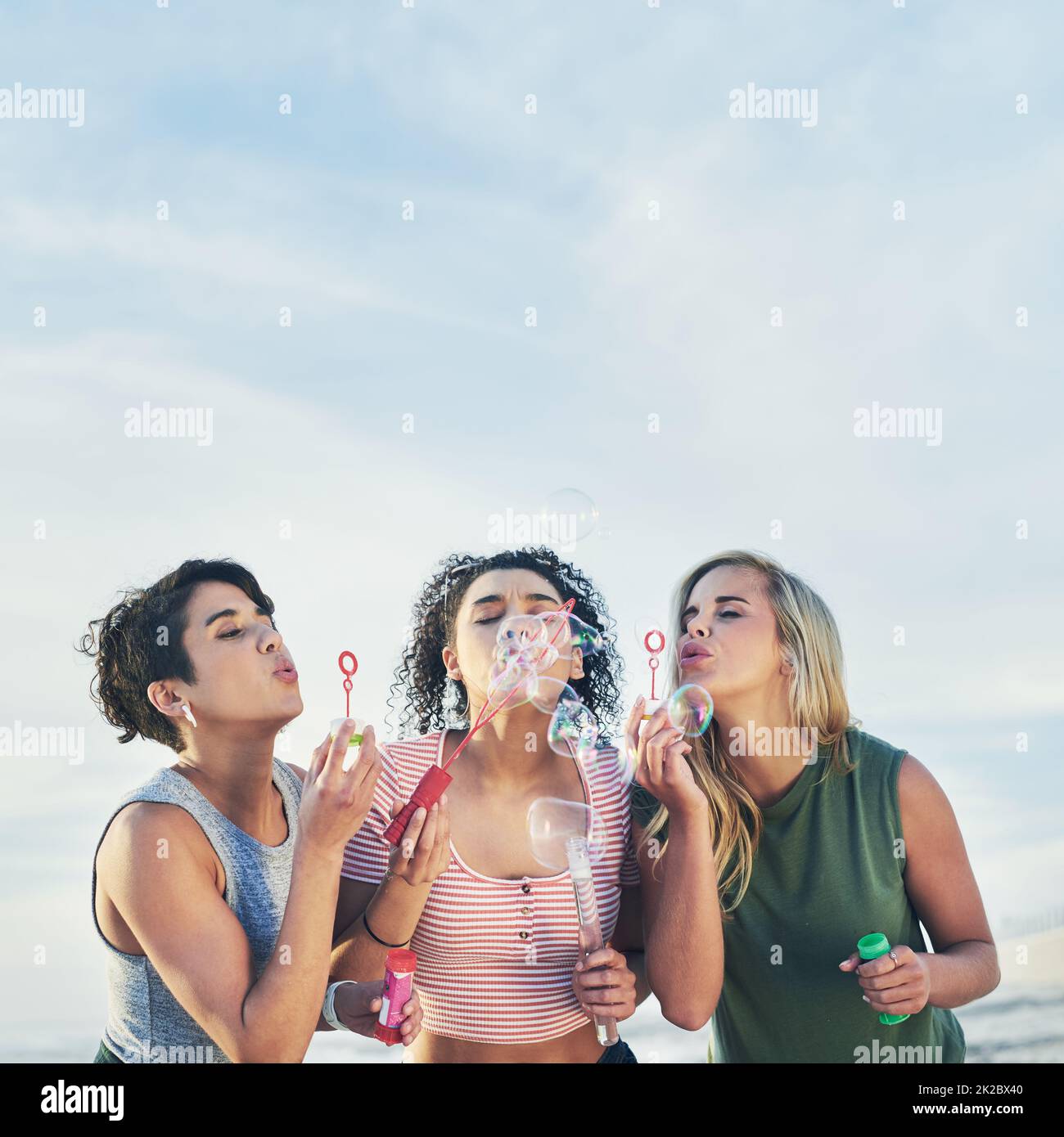 Beffe. Scatto corto di tre amici che soffia bolle sulla spiaggia. Foto Stock