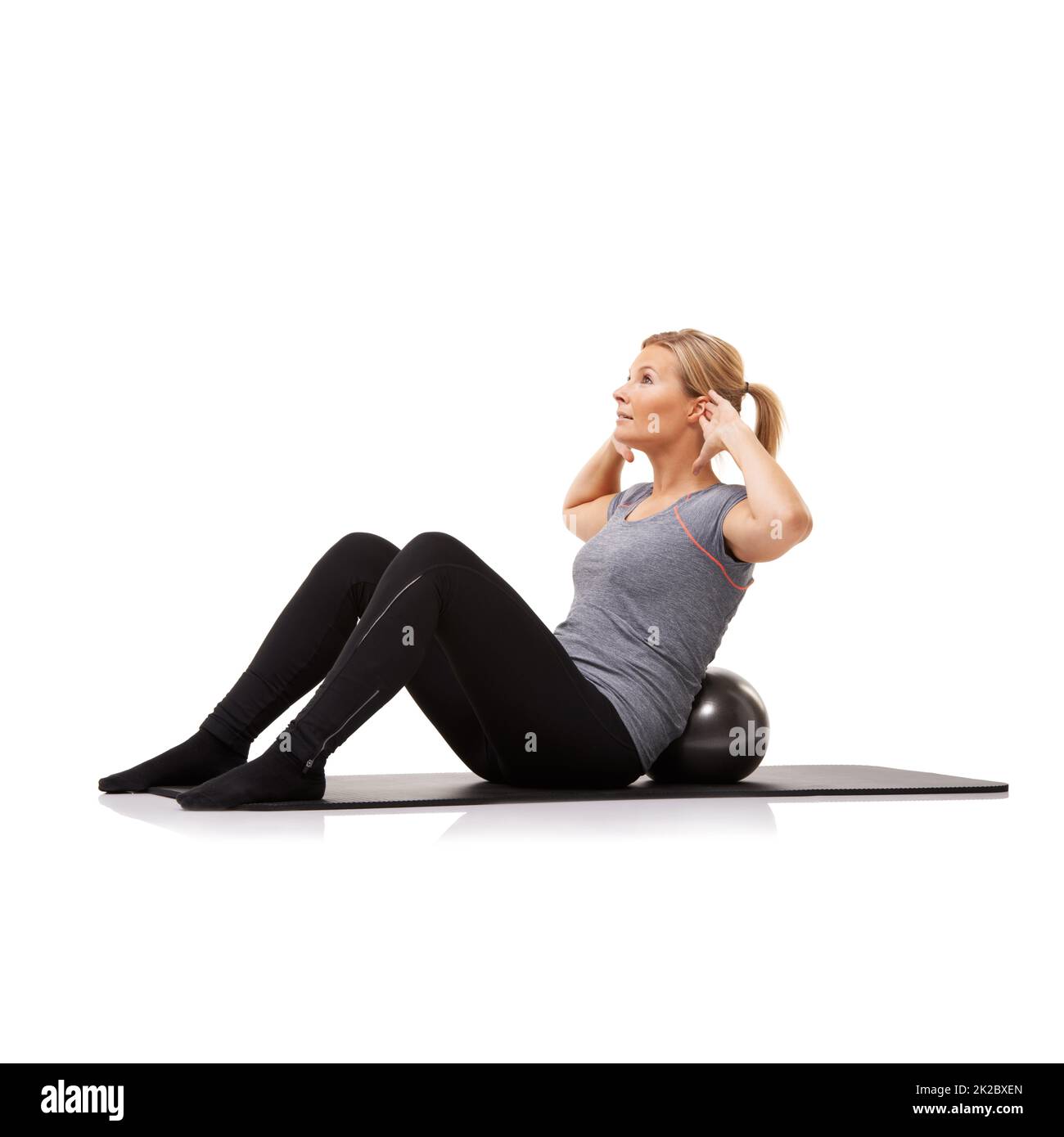 Shes lotta fit. Una giovane donna che fa sit-up su una sfera di esercitazione mentre isolata su uno sfondo bianco. Foto Stock