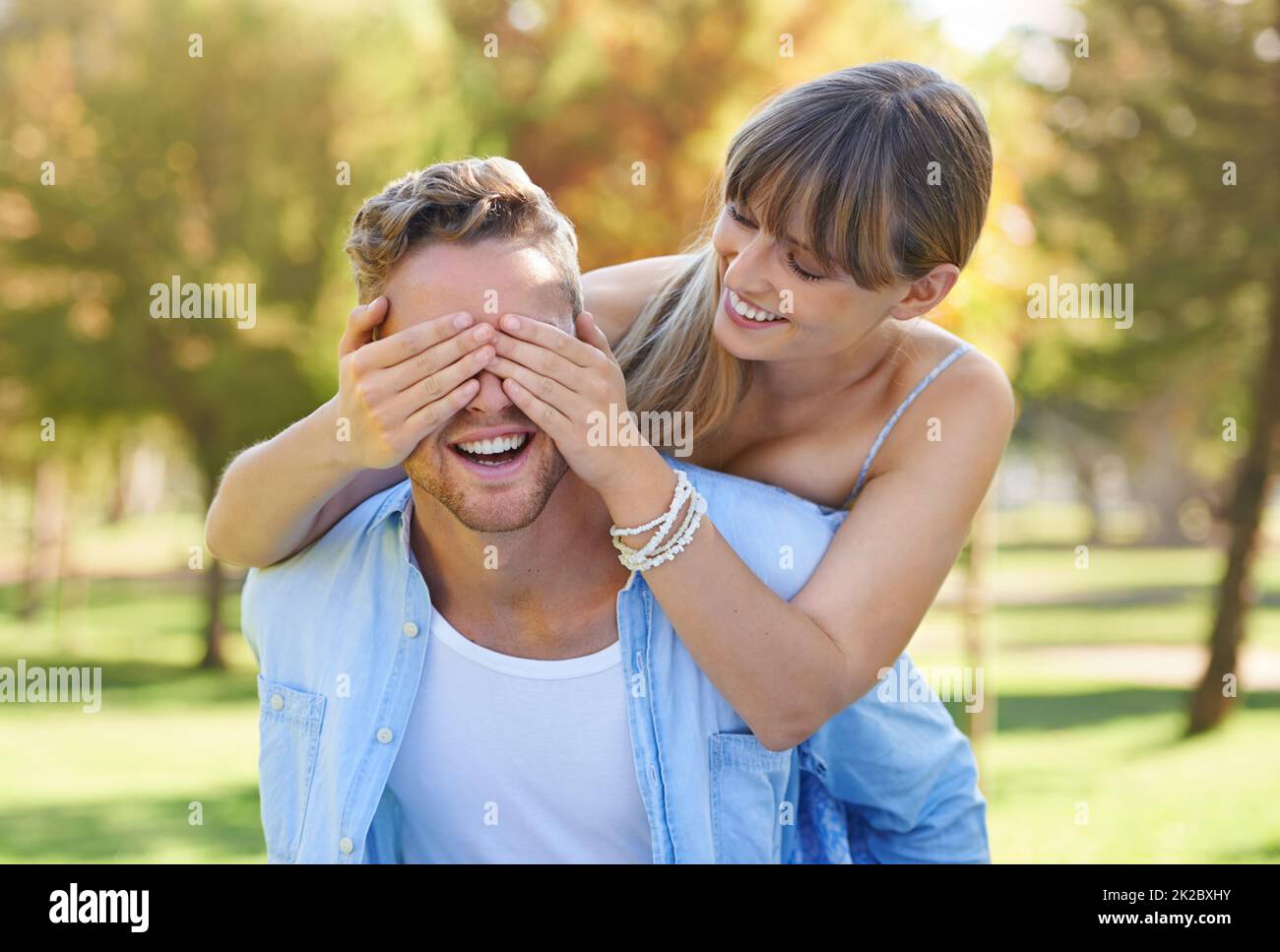 Non guardare. Un uomo che dà alla sua ragazza un piggyback mentre lei copre gli occhi nel parco. Foto Stock