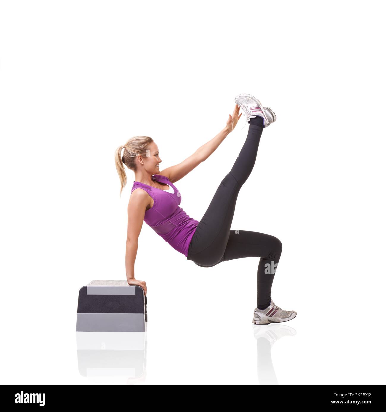Bilanciamento e tono. Una giovane donna sorridente che fa aerobica su un punto aerobico isolato su uno sfondo bianco. Foto Stock