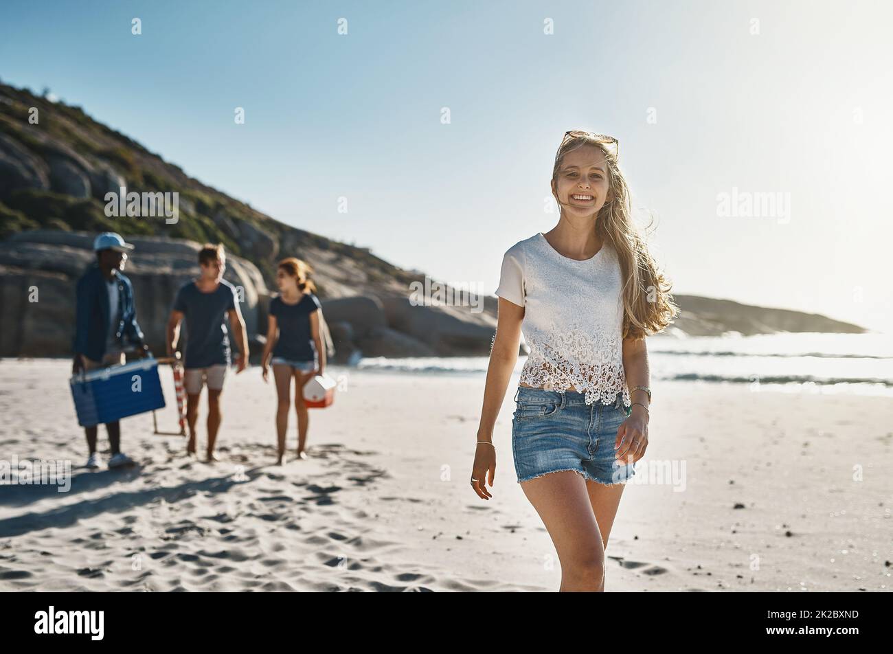 Im solo felice di essere con i miei amici. Ritratto di una giovane donna felice che cammina sulla spiaggia con i suoi amici in una giornata di sole. Foto Stock
