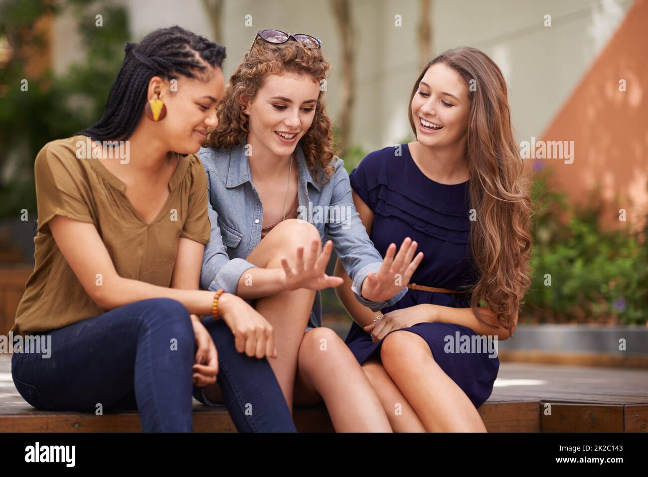 Ooh ragazze, controllare questo manicure. Un gruppo di giovani donne sedute all'aperto ammirando le unghie di un amico. Foto Stock