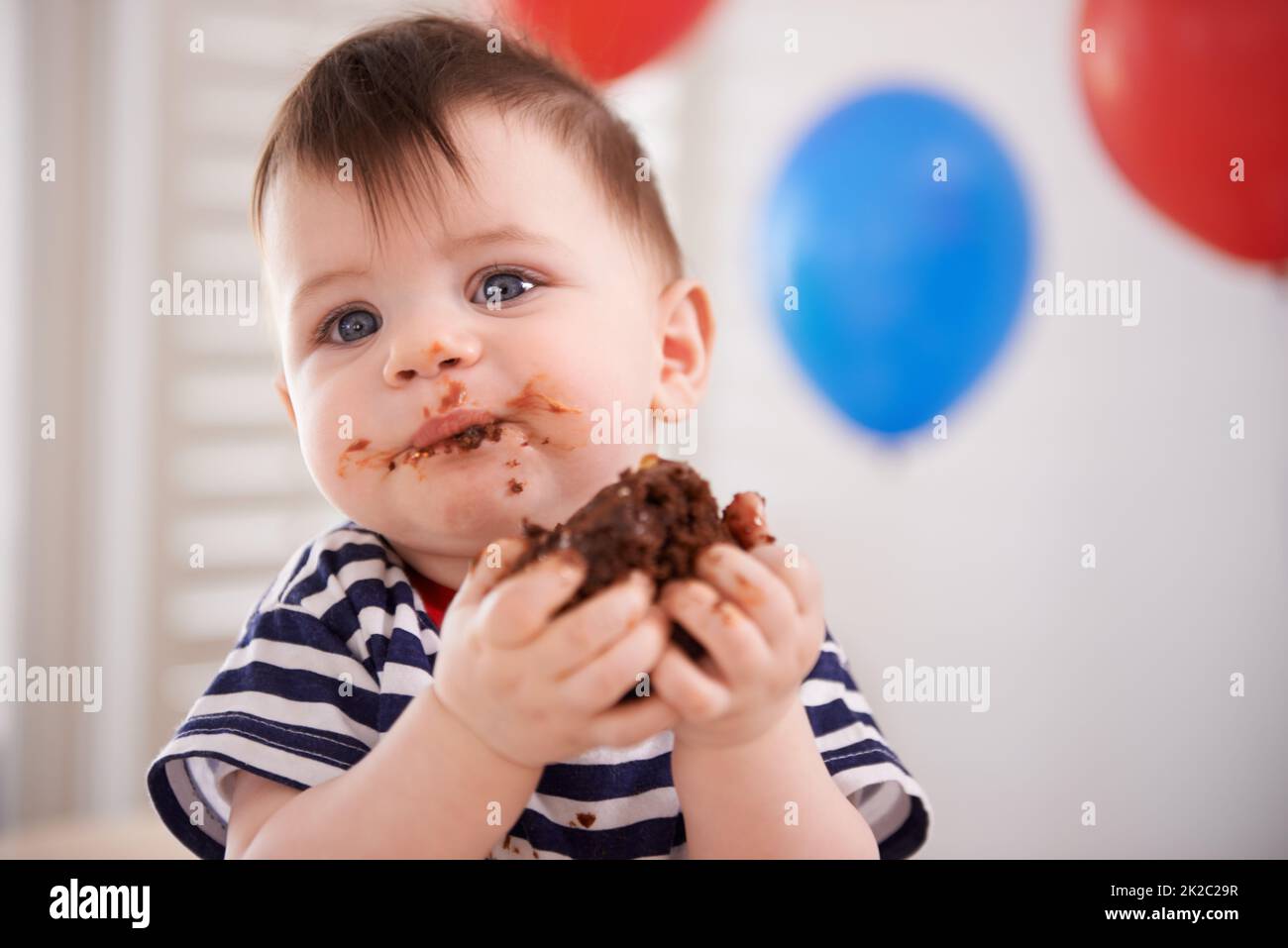 Il suo compleanno... HES permesso di indulgere. Scatto di un bambino che mangia una torta al suo compleanno. Foto Stock