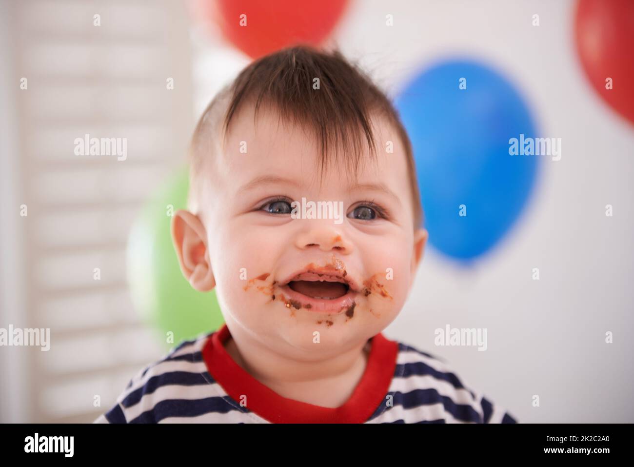 Mmm...cake. Ritratto di un bambino al suo compleanno. Foto Stock