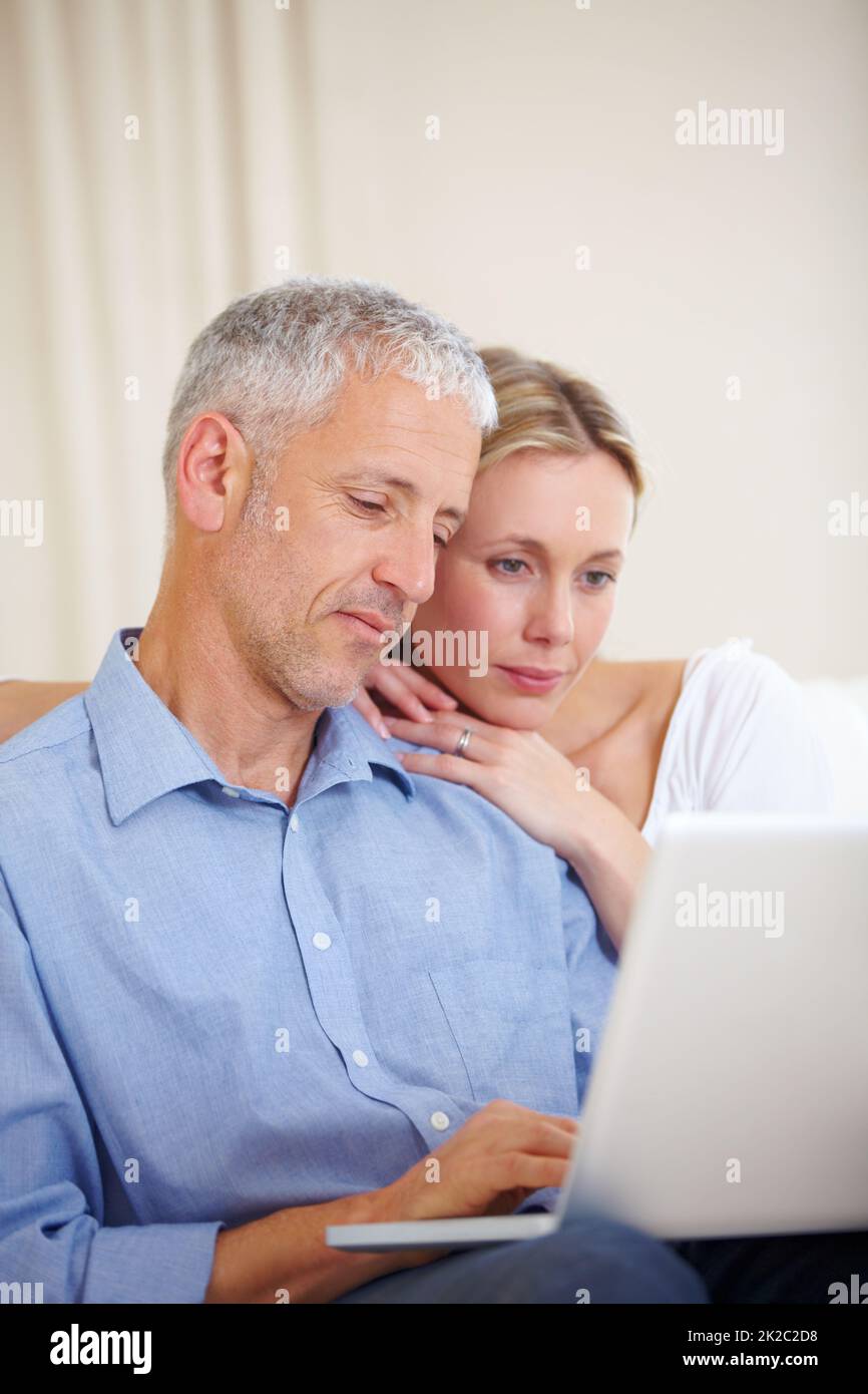 Chat online. Una coppia sposata seduta con il loro portatile a casa. Foto Stock