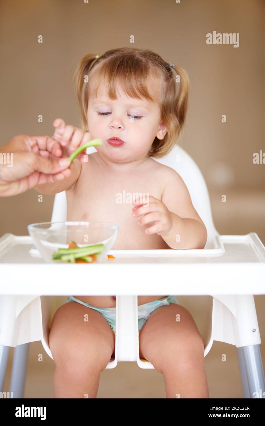 Snacking sano. Una ragazza piccola carina che è alimentata da sua madre. Foto Stock