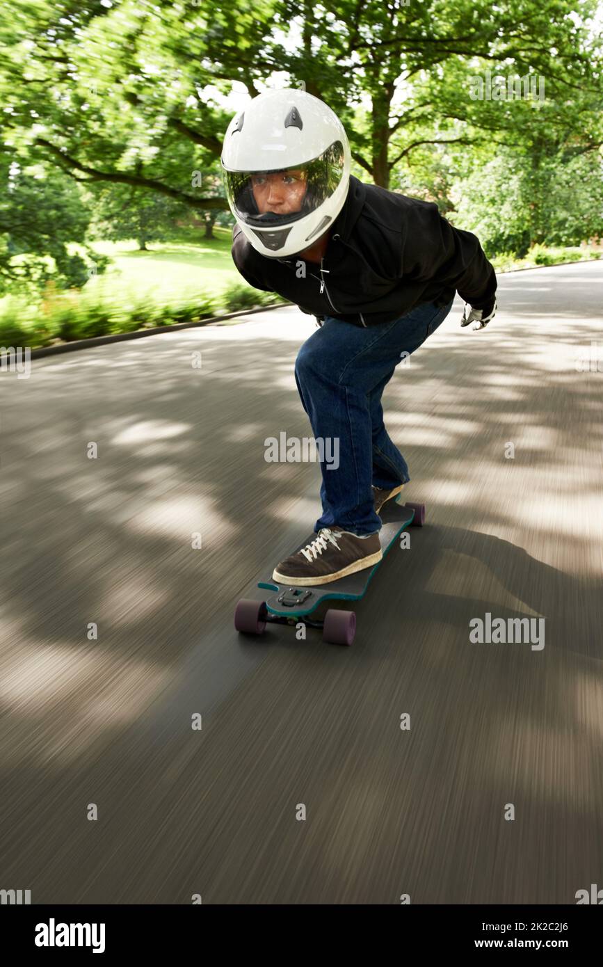 Aumentare la velocità. Colpo di un uomo che skateboard lungo una corsia ad alta velocità sulla sua tavola. Foto Stock