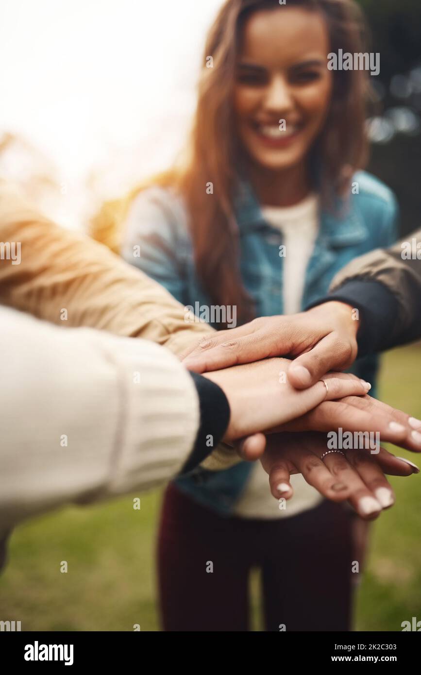 Sappiamo anche come essere un team. Girato di un gruppo di giovani amici allegri che formano un huddle con le loro mani insieme all'esterno durante il giorno. Foto Stock