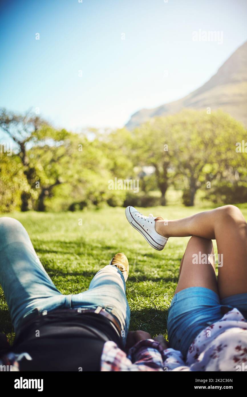 La vita è piena di bei momenti. Scatto corto di una giovane coppia sdraiata sull'erba del parco. Foto Stock