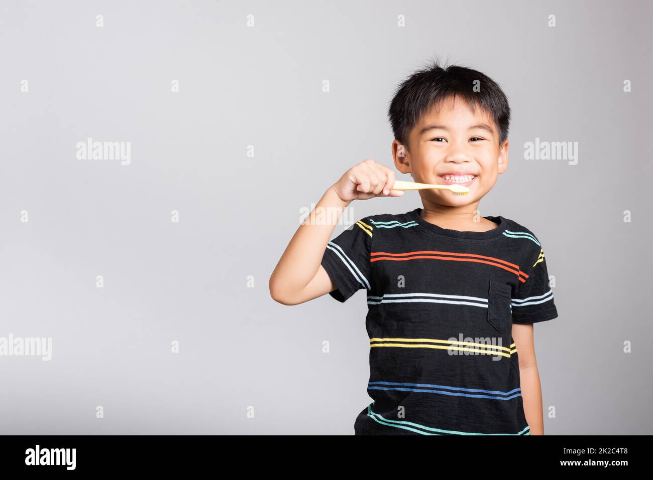 Piccolo carino ragazzo 5-6 anni spazzolando i denti e sorridere in studio scatto isolato Foto Stock