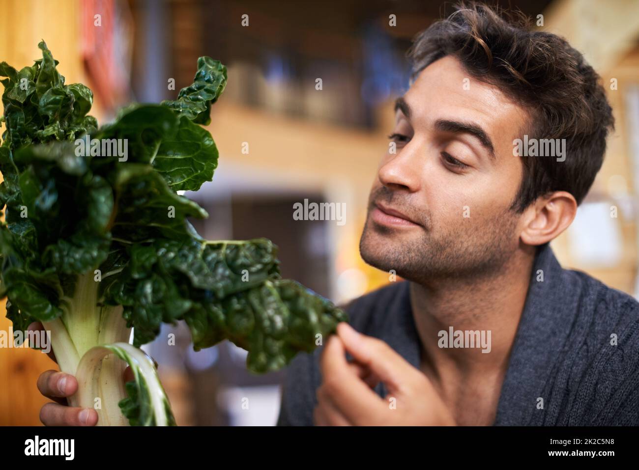 Ispezione del prodotto. Scatto di un giovane che sceglie quale spinaci comprare. Foto Stock