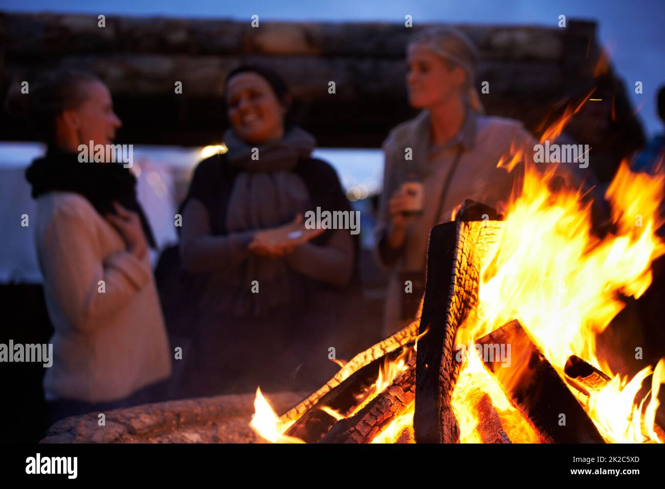 Ottenere un po 'di calore nella notte. Scatto corto di persone in piedi intorno ad un fuoco. Foto Stock