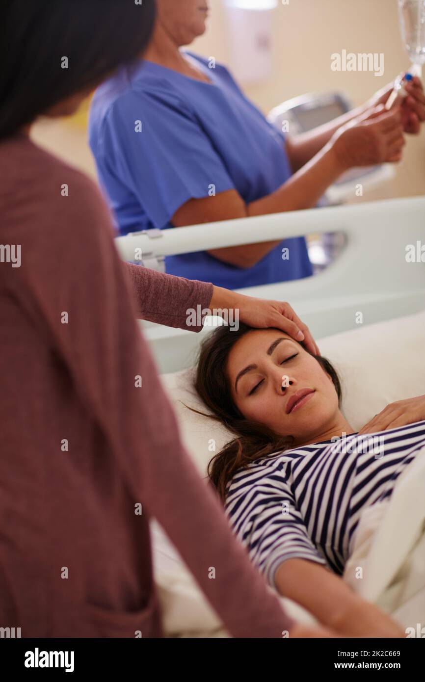 Ottenga presto Scatto di una donna che tocca la fronte dei suoi amici mentre lei si trova nel suo letto d'ospedale. Foto Stock