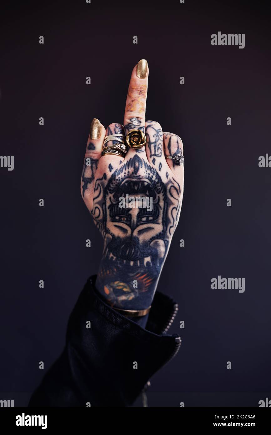 Atteggiamento tatuato. Scatto di una donna tatuata che dà il dito alla fotocamera. Foto Stock