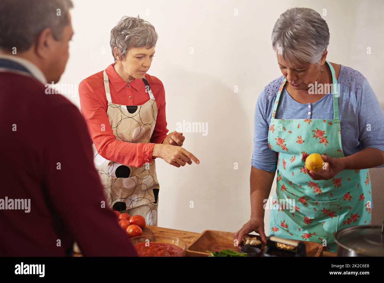 Indossate il grembiule e montate qualcosa di incredibile. Shot di un gruppo di anziani che cucinano in cucina. Foto Stock