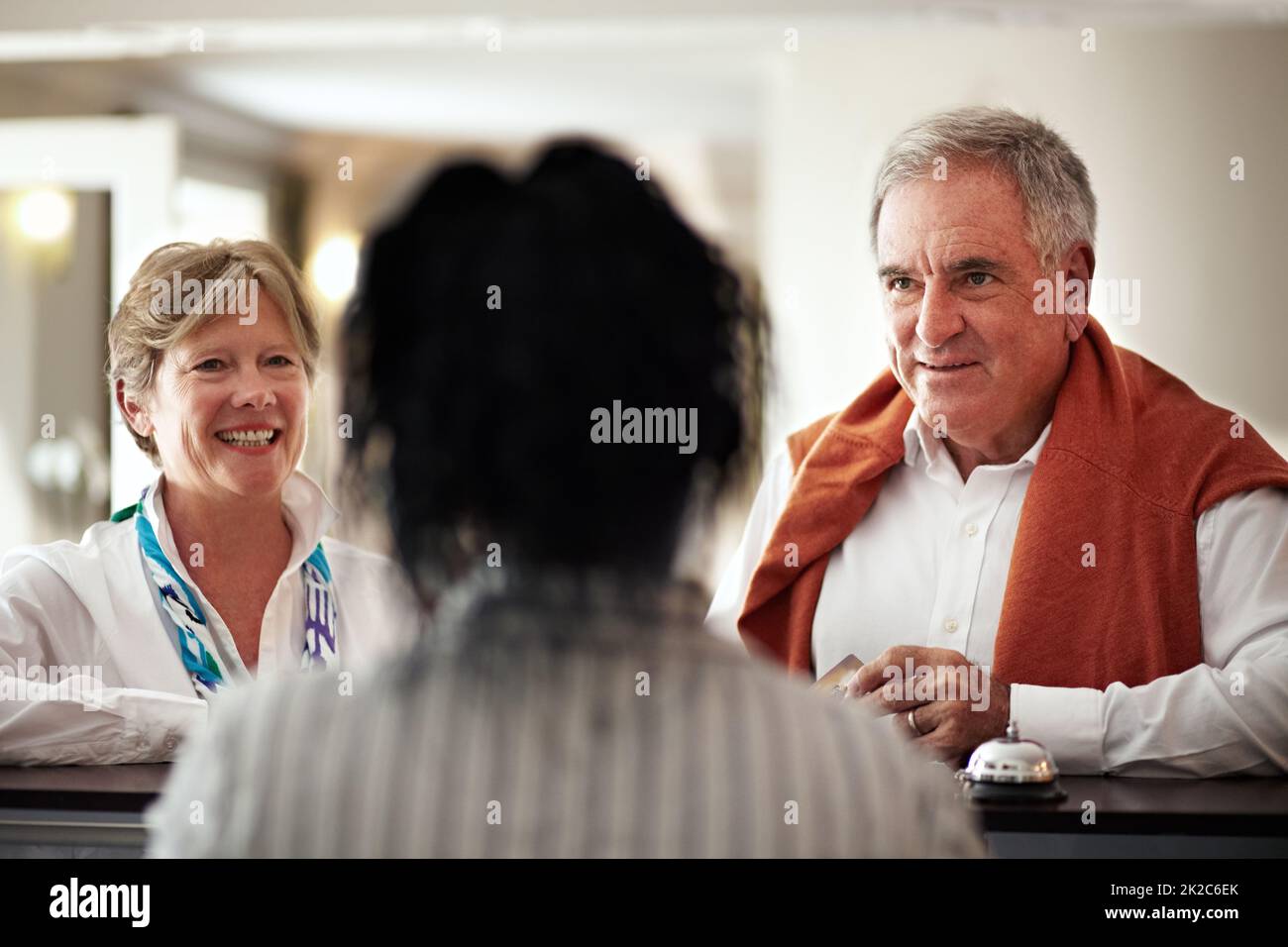 Benvenuto. Ci auguriamo che il vostro soggiorno sia piacevole. Scatto corto di una coppia anziana che effettua il check-in in hotel. Foto Stock