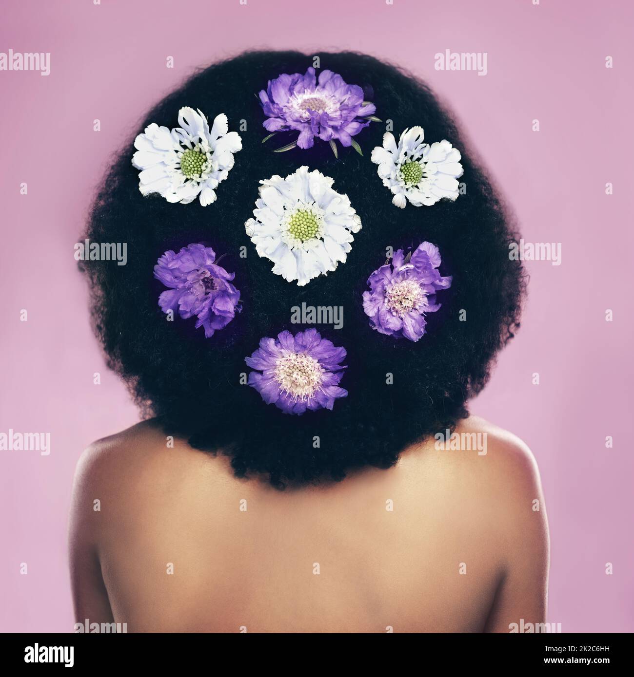 I fiori sono ovunque. Scatto retroguarato di una donna in piedi con fiori nei suoi capelli. Foto Stock