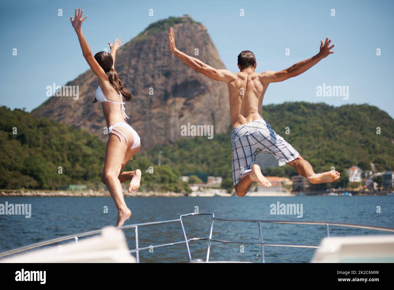 Vai selvaggio questa vacanza. Vista posteriore di una giovane coppia che salta da uno yacht nell'oceano. Foto Stock