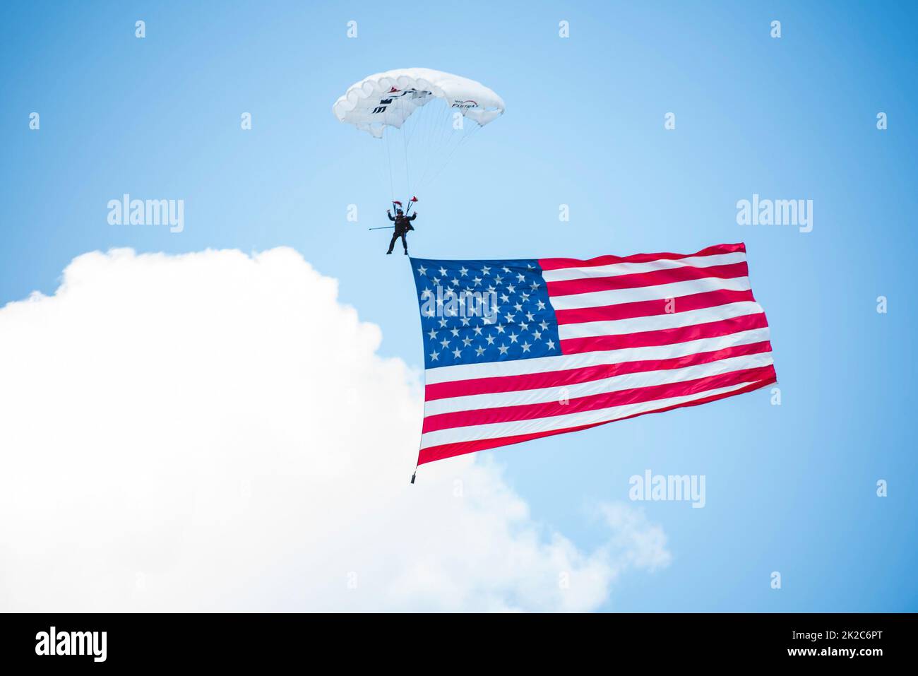 Un paracadutista scivola giù con la bandiera americana a terra set. 17, 2022 al dopo-party della Air Force Marathon tenutosi a Greene, Beavercreek, Ohio. L'after-party ha rivelato i velivoli in evidenza per l'evento del prossimo anno e celebrato con varie attività per concludere la gara di quest'anno. (STATI UNITI Air Force foto di Hannah Carranza) Foto Stock