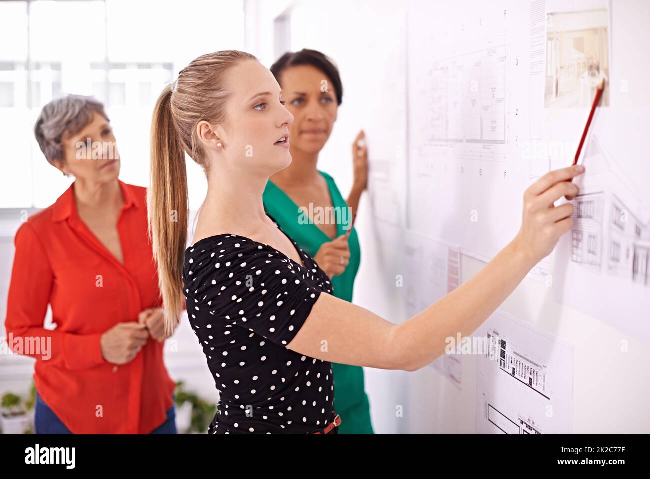 Evidenziando le caratteristiche importanti dei suoi piani. Foto di un gruppo di architetti femminili che lavorano insieme su un progetto. Foto Stock