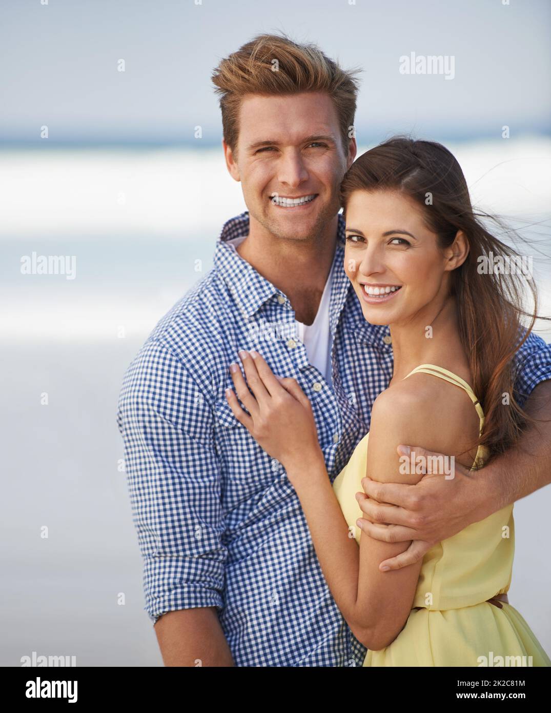 Il nostro amore è per sempre. Una giovane coppia che abbraccia felicemente la spiaggia. Foto Stock