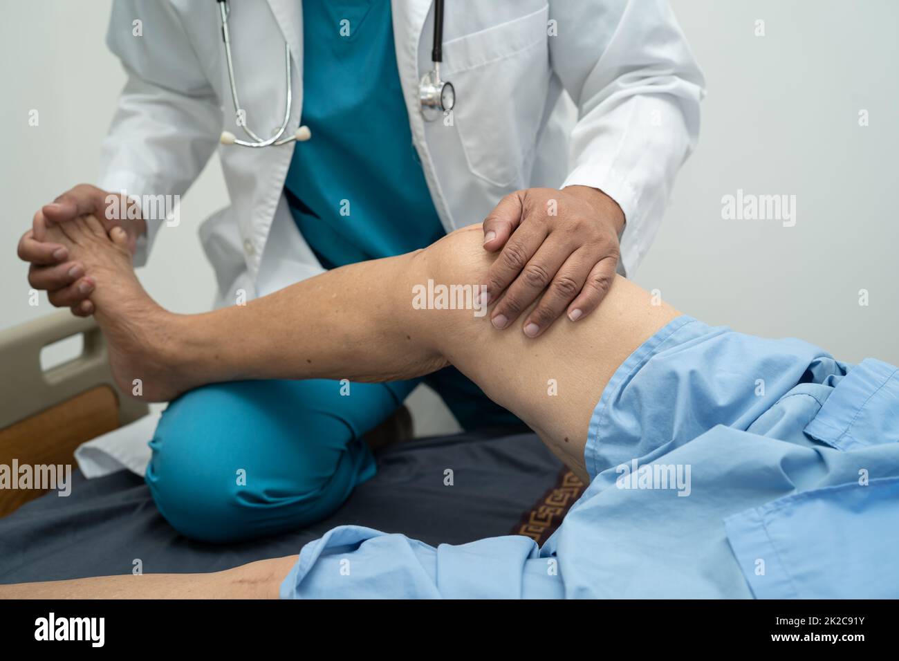 Medico asiatico fisioterapista esame, massaggio e trattamento ginocchio e gamba di paziente anziano in ospedale medico ambulatorio ortopedist infermiere. Foto Stock
