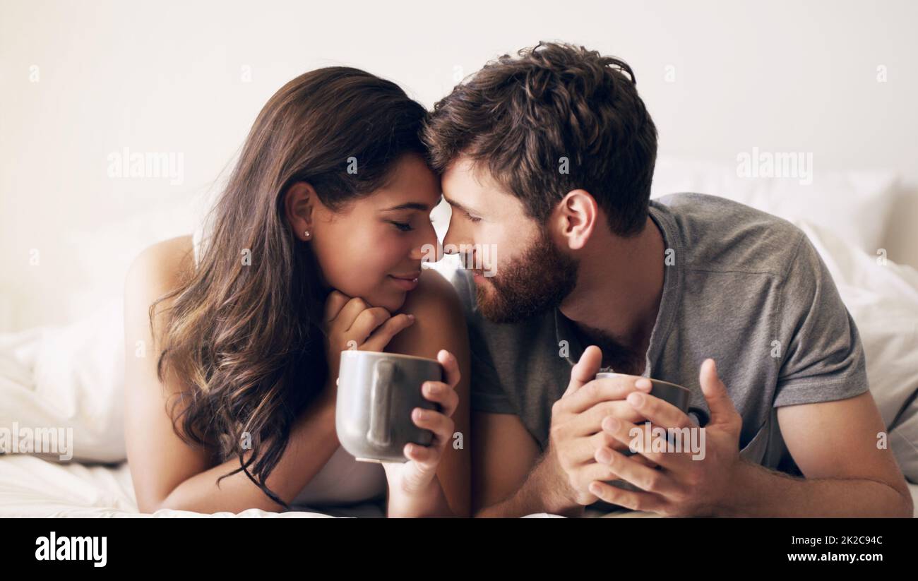 Caffè e tempo di qualità, perfezione. Shot di una giovane coppia felice che ha un caffè insieme a letto a casa. Foto Stock